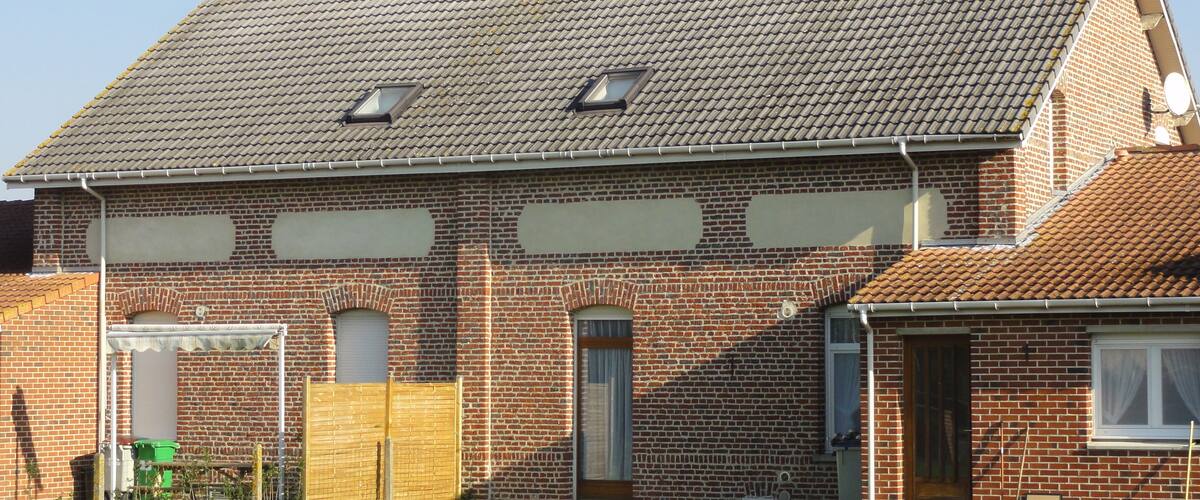 A brick house with a tiled roof and two satellite dishes.