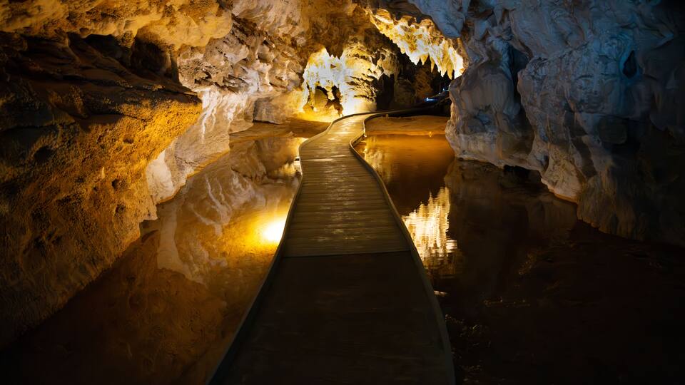 A cave with a reflective water surface and a wooden walkway.