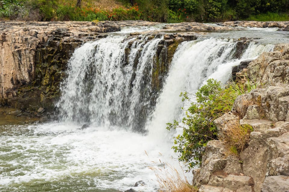 A waterfall cascading over rocky terrain with lush greenery around.