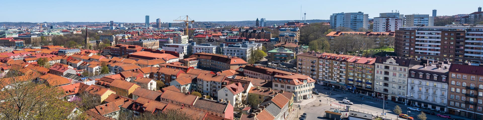 A cityscape with red-roofed buildings, a prominent tower, and a clear blue sky.