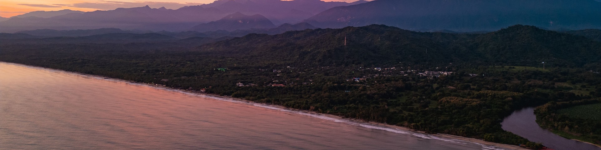 A coastal landscape with mountains in the background and a river running through the terrain.