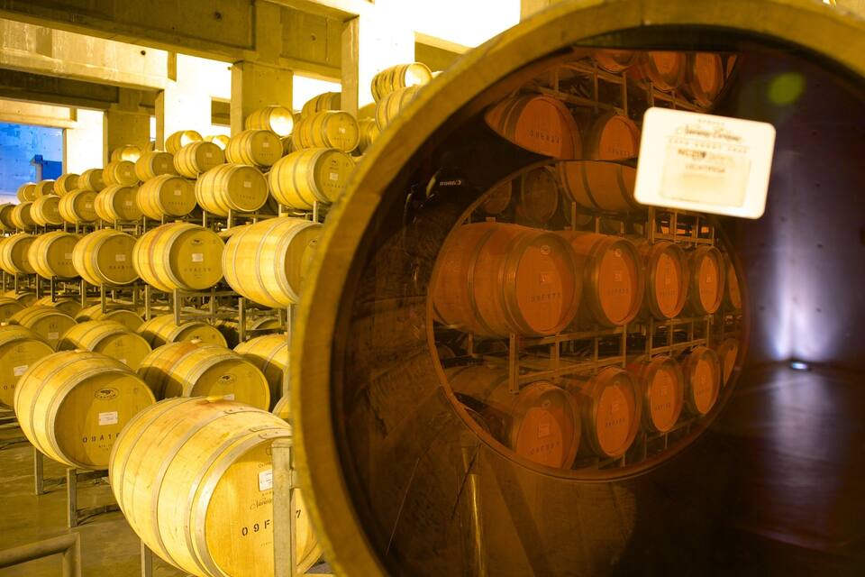 Un vaste espace de stockage de barriques de vin, où de nombreuses barriques en bois sont empilées en rangées.