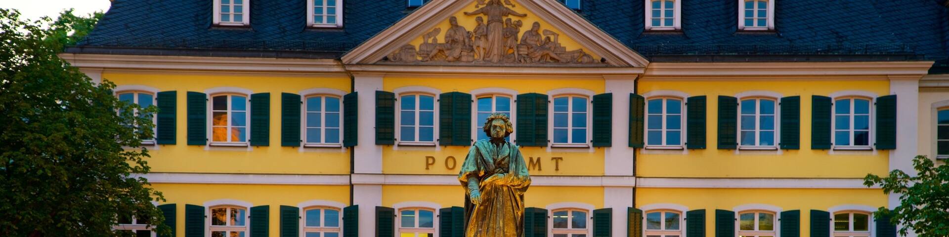 A statue in front of a yellow building with green shutters.