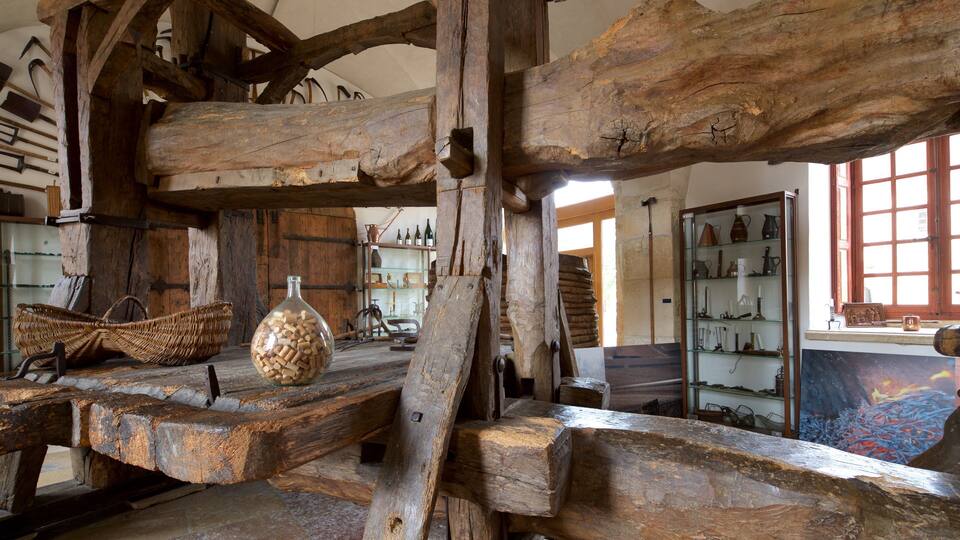 A rustic interior with wooden beams, stone walls, and various antique items on shelves.