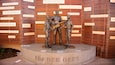 A bronze statue of The Bee Gees performing, surrounded by wooden slats with song lyrics.