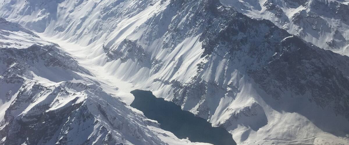 A snow-covered mountain range with a prominent peak and a glacial valley.