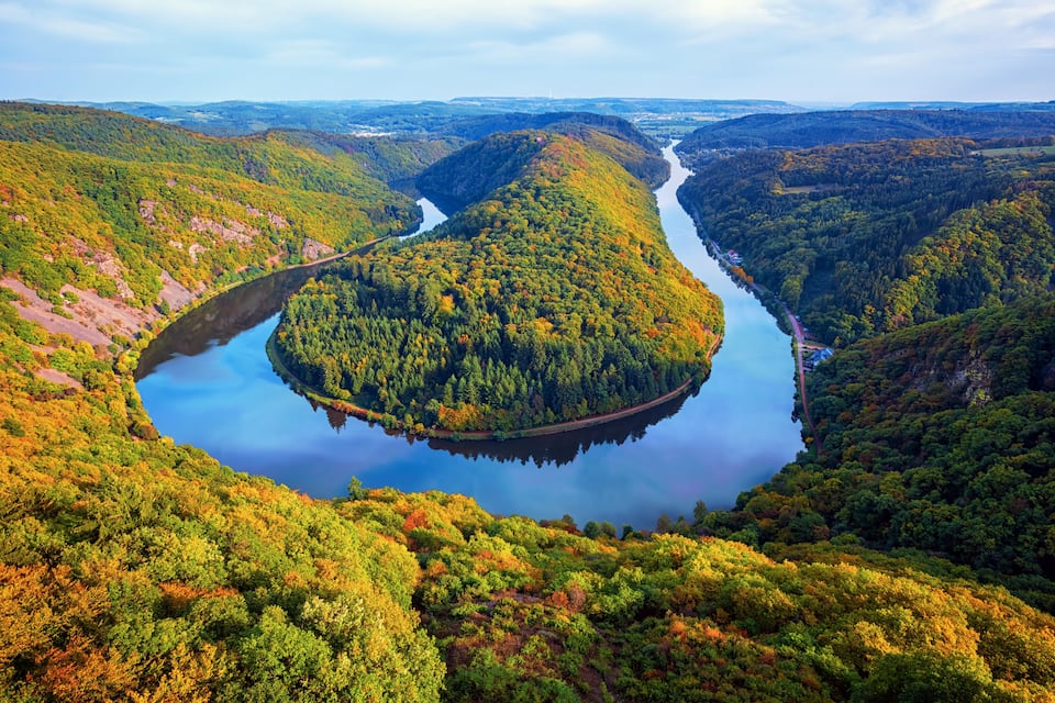 A river winding through a forested valley with a bridge crossing over it.
