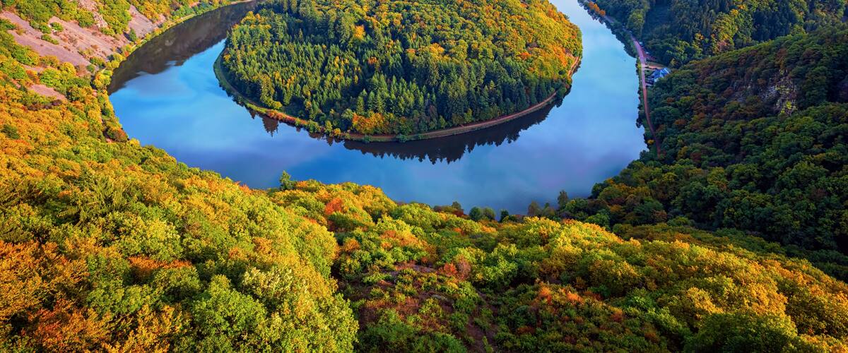 A river winding through a forested valley with a bridge crossing over it.