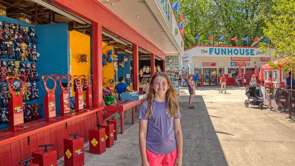A girl standing in front of a store with a sign that reads "The Funhouse."