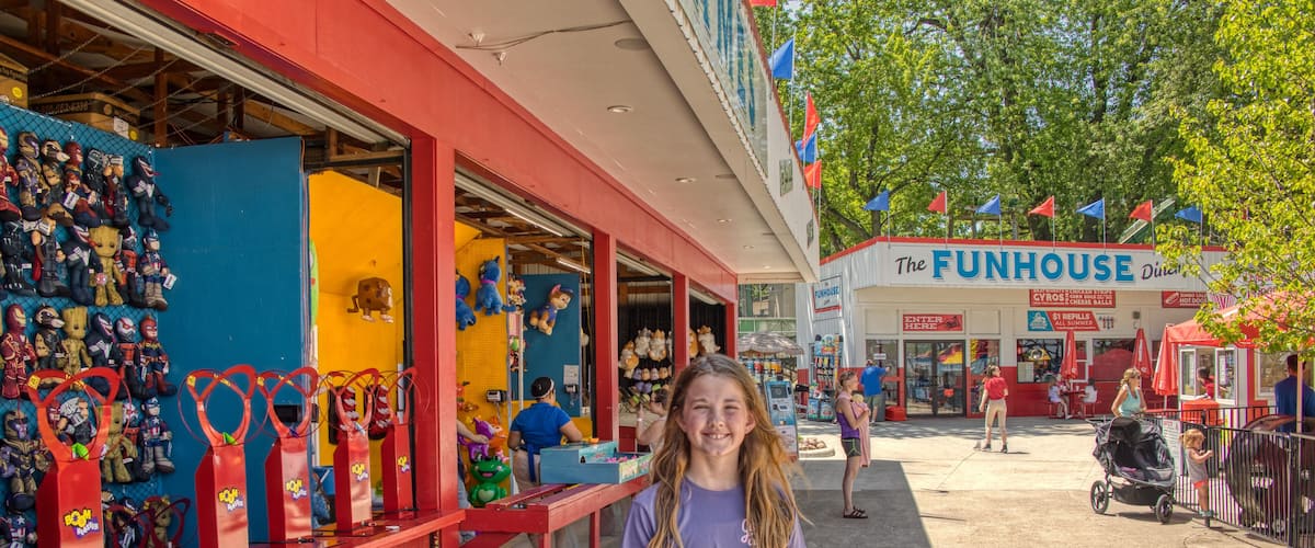 A girl standing in front of a store with a sign that reads "The Funhouse."