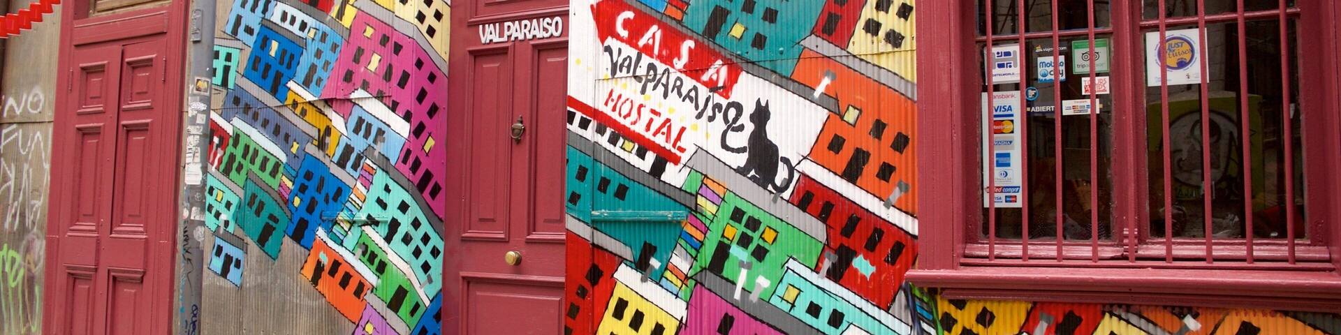 A colorful building facade with a vibrant mural of buildings and a sign for Valparaiso Hostel.