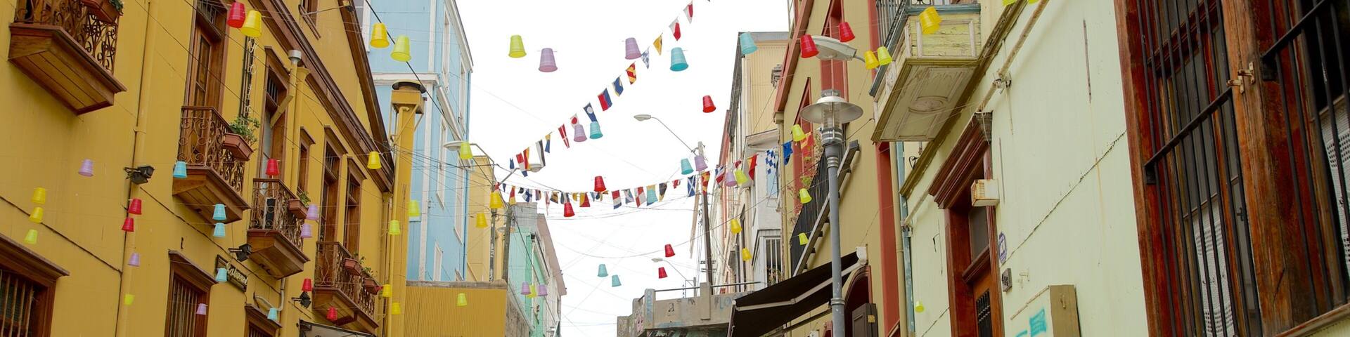 A narrow street with colorful flags, balconies, and potted plants.