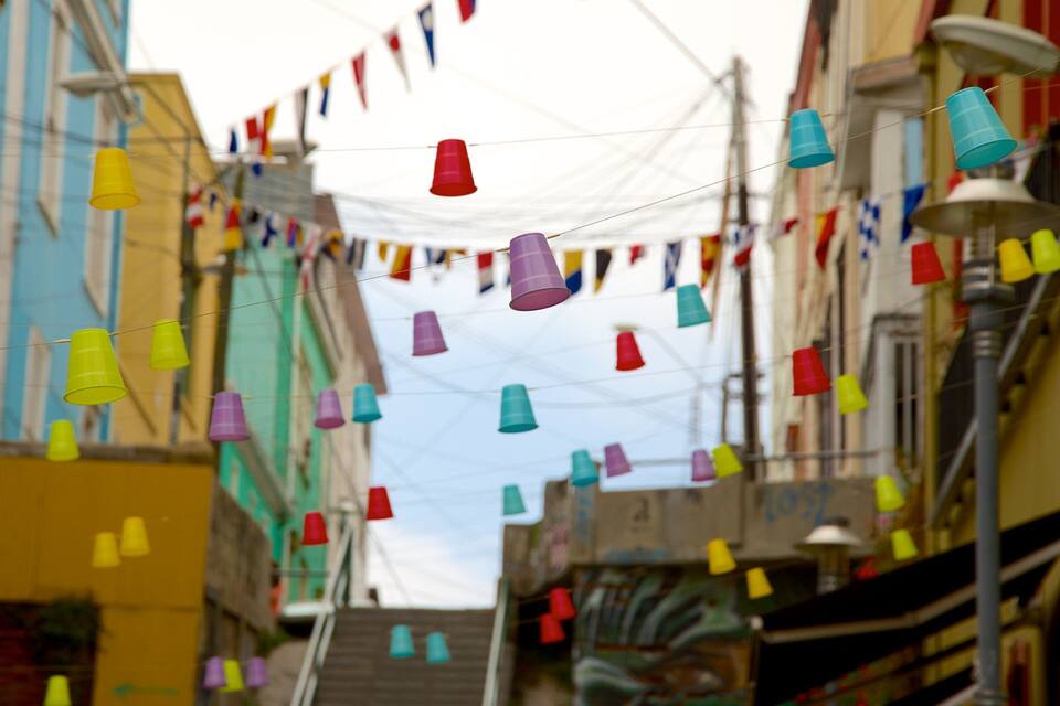 A narrow street with colorful plastic cups hanging from wires, creating a festive atmosphere.