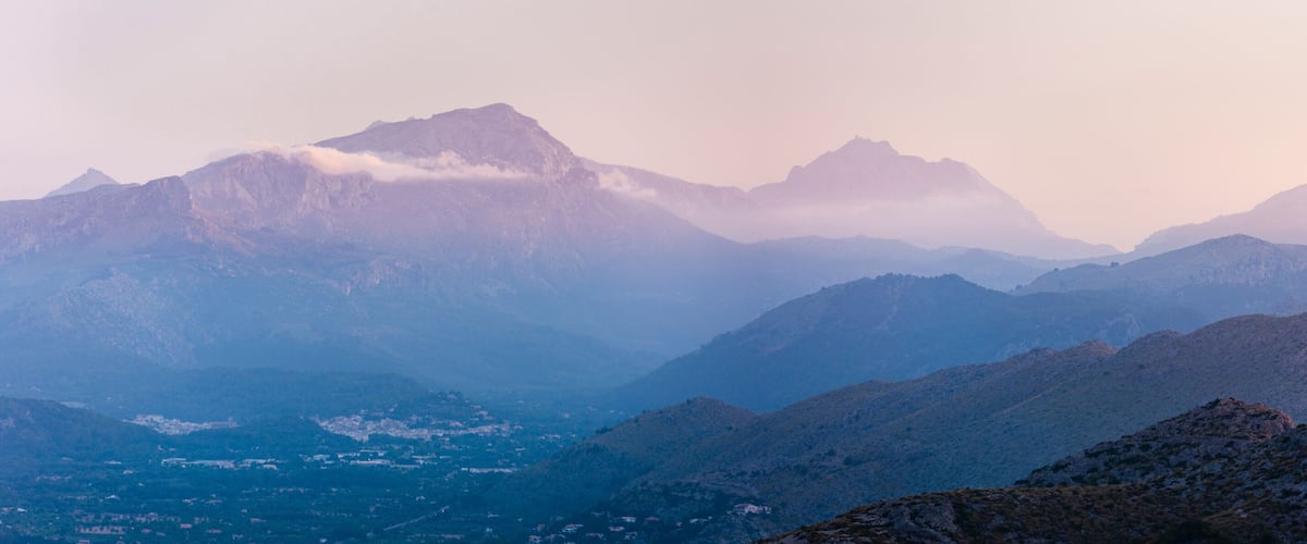 A mountainous landscape with rugged peaks and a valley below.