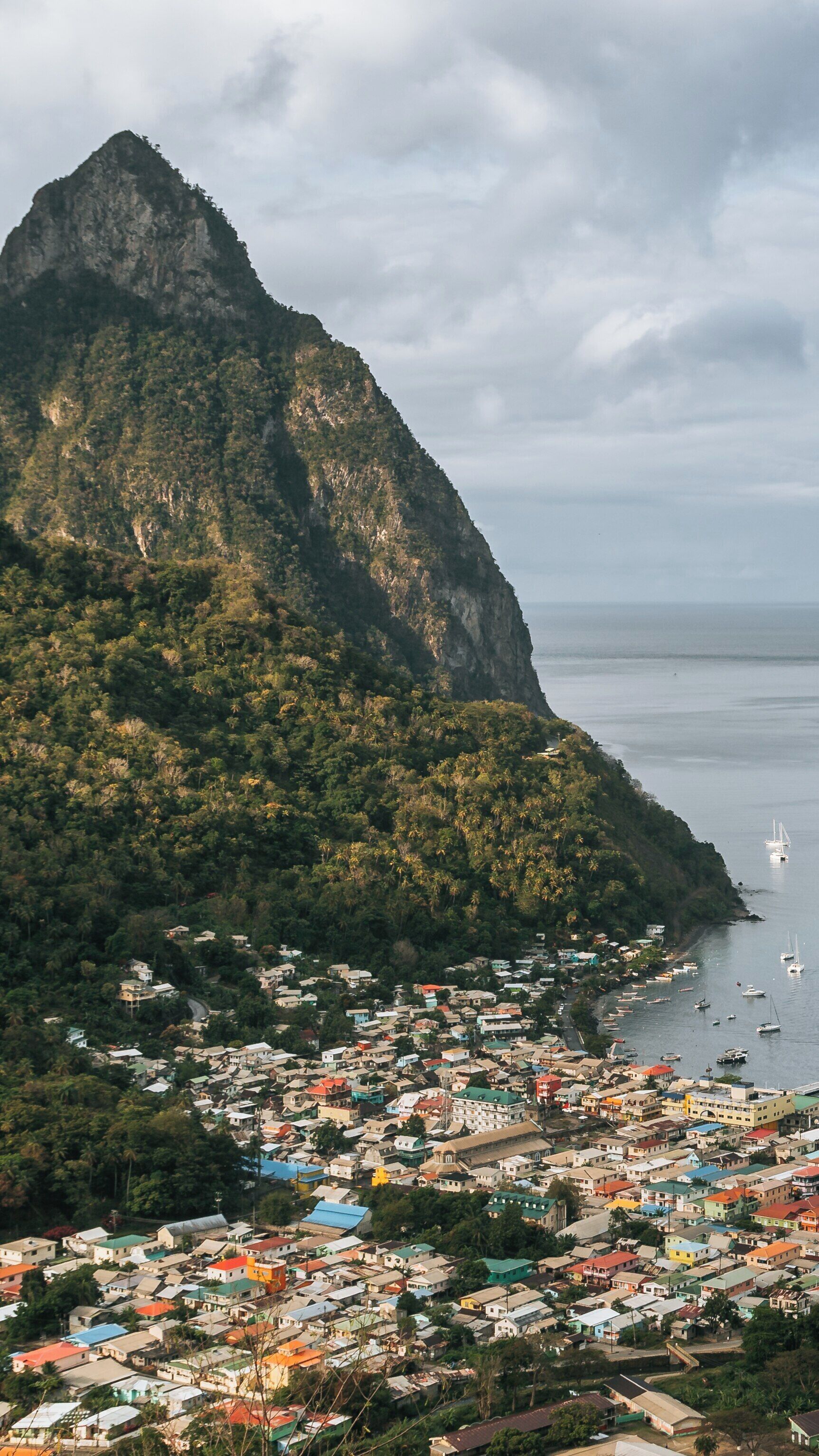 Gros Piton rises majestically above the town of Soufriere in St. Lucia, overlooking the Caribbean Sea at sunset