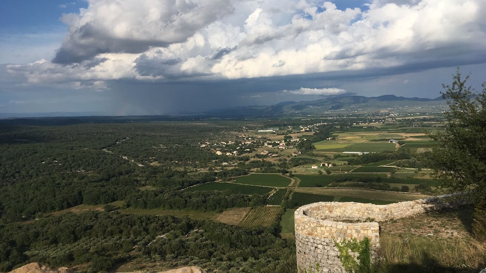 Un paysage rural avec une tour de pierre, des champs et un village situé dans la vallée.