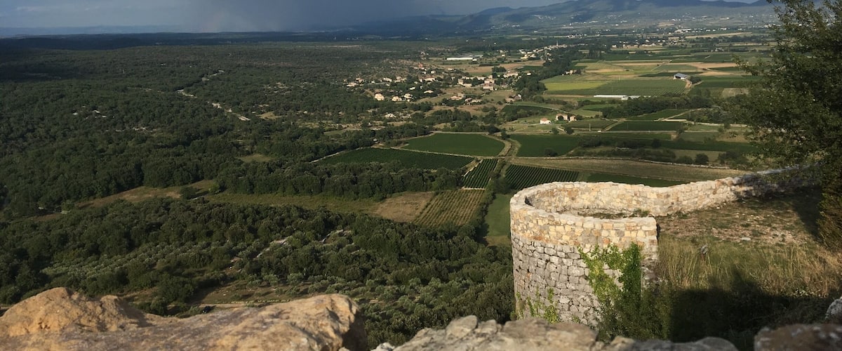 A rural landscape with a stone tower, fields, and a village in the valley.