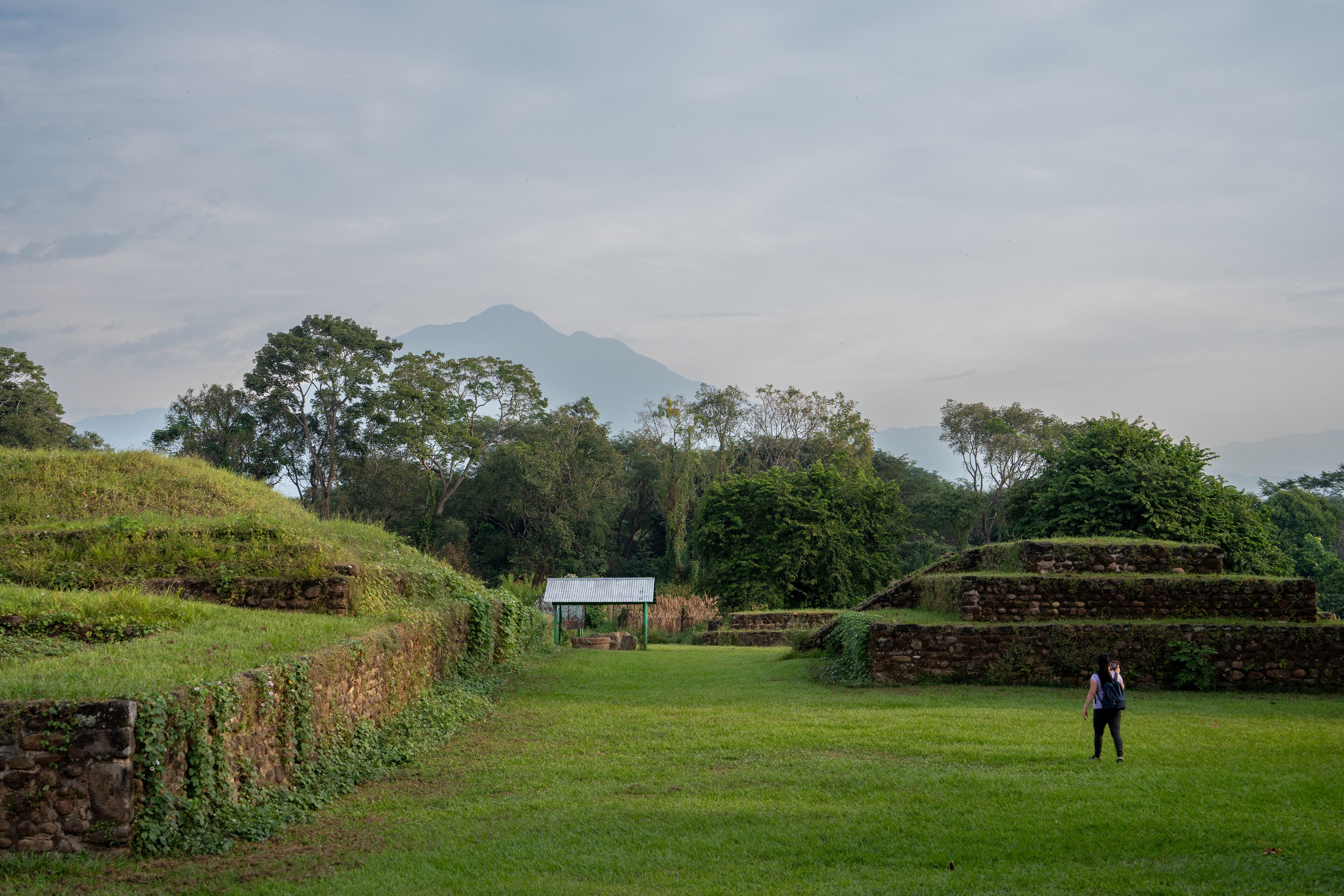 A grassy field with stone walls and a small shelter.