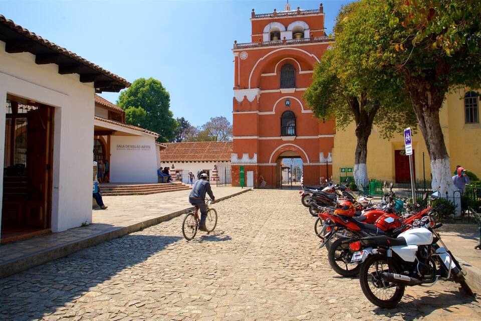A cobblestone street leading to a historic building with a bell tower.