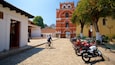 A cobblestone street leading to a historic building with a bell tower.