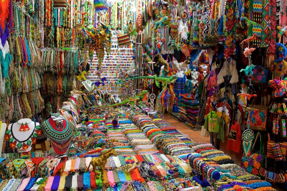 Um mercado vibrante repleto de tecidos coloridos, joias e acessórios.