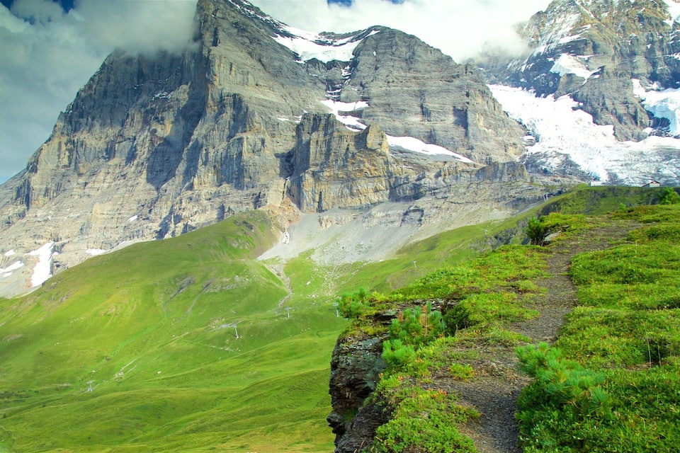 Paisaje montañoso con un pico destacado, un glaciar y un valle verde.