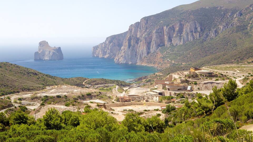 A coastal village with rocky cliffs, a large rock formation in the sea, and a winding road.
