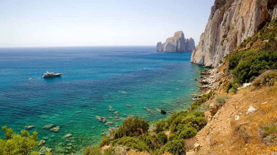 A coastal landscape with a yacht on clear turquoise waters, rocky cliffs, and lush greenery.