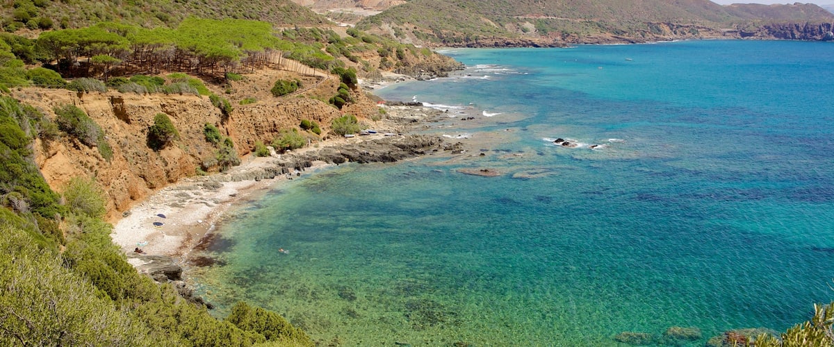 A coastal landscape with clear turquoise waters, rocky cliffs, and green vegetation.