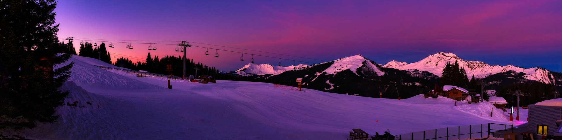 Una pista de esquí cubierta de nieve al anochecer, con una montaña al fondo.