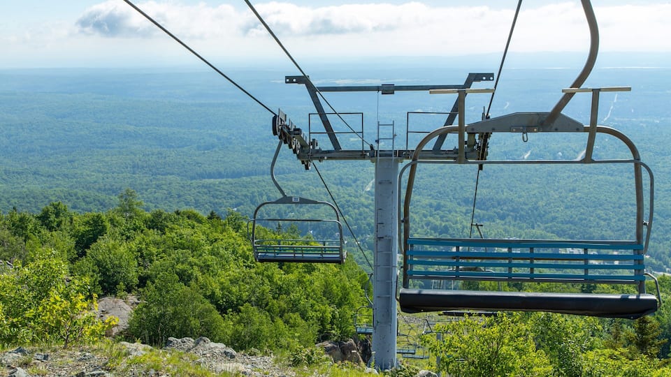 A cable car system with a view of a forested landscape and distant mountains.