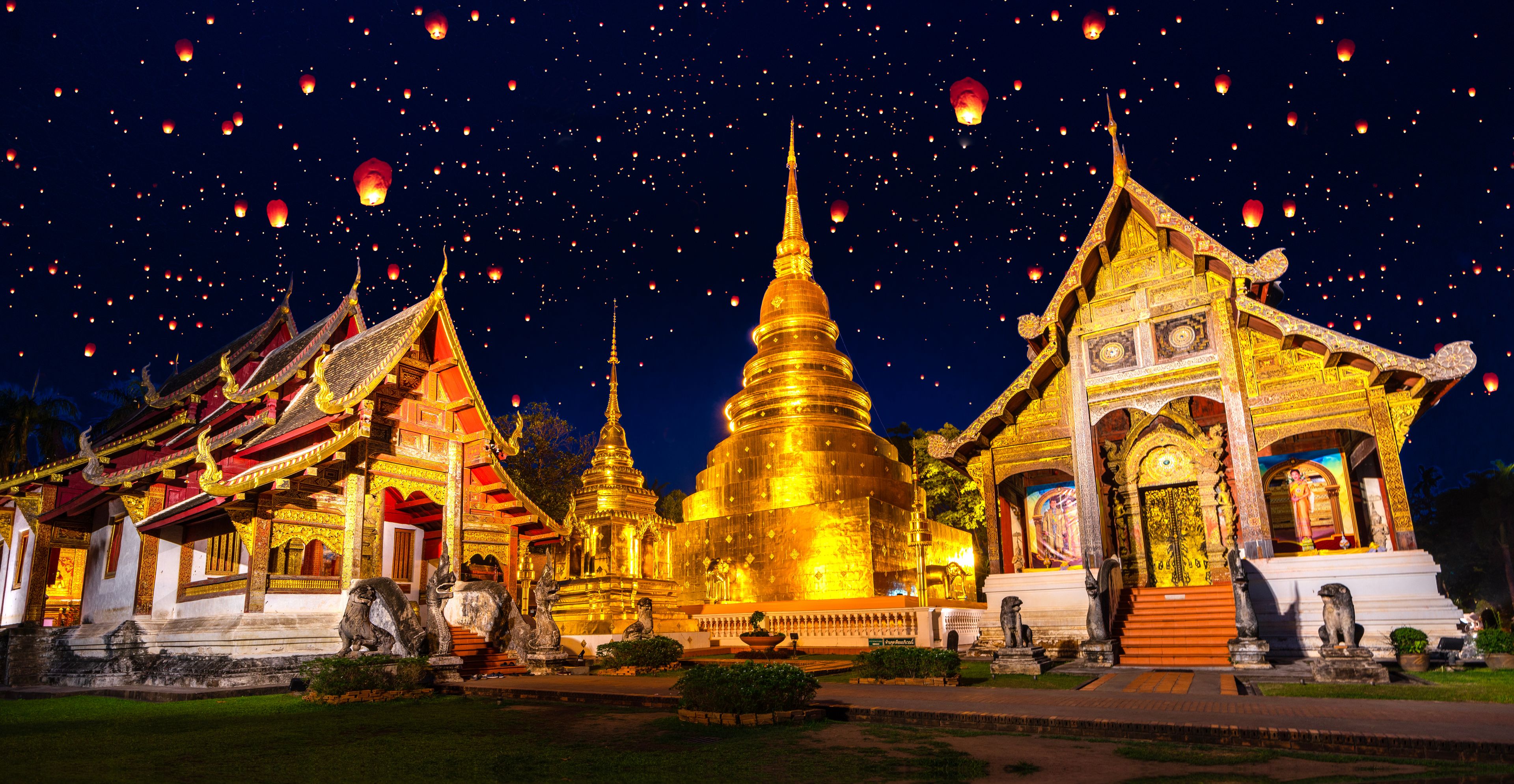Un ensemble de temples aux flèches dorées et à l’architecture traditionnelle, illuminé la nuit.