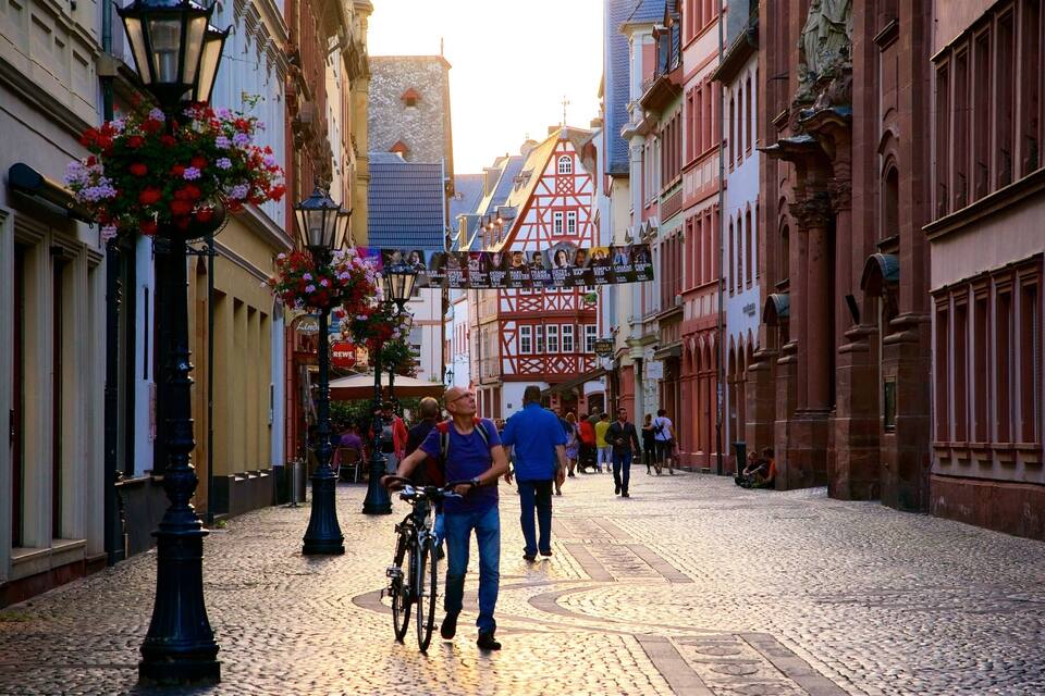A cobblestone street lined with historic buildings, a bicycle, and people walking.