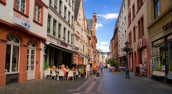 Une rue pavée bordée de bâtiments historiques, de cafés en plein air et de diverses boutiques.