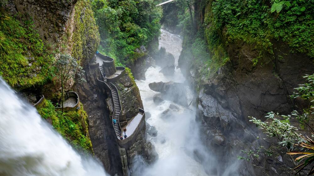 A waterfall cascading through a rocky gorge with a narrow path for visitors.