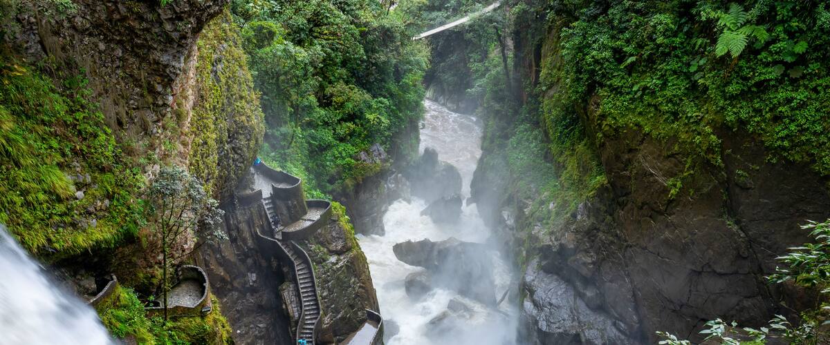 A waterfall cascading through a rocky gorge with a narrow path for visitors.