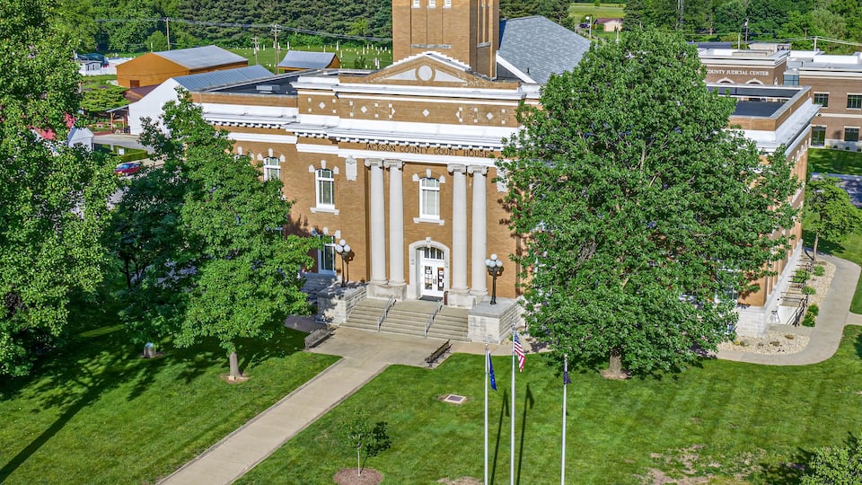 A courthouse with a clock tower, surrounded by green lawns and trees.
