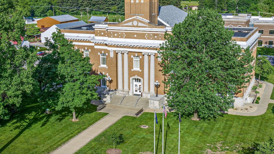 A courthouse with a clock tower, surrounded by green lawns and trees.