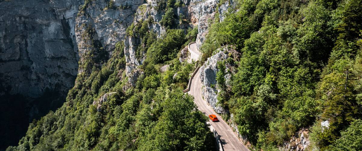 A winding mountain road surrounded by dense forests and rocky cliffs.