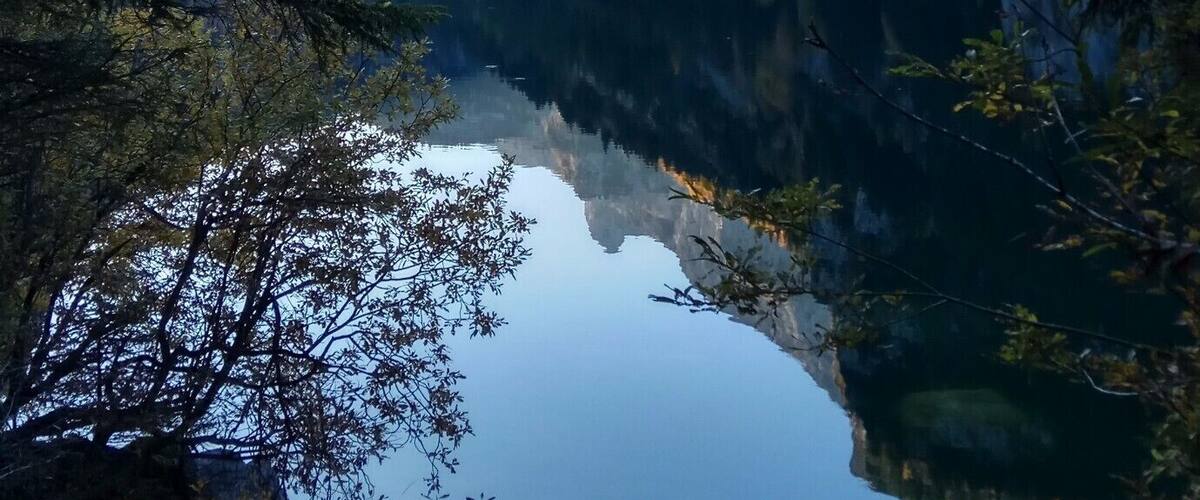A calm lake surrounded by mountains and trees.