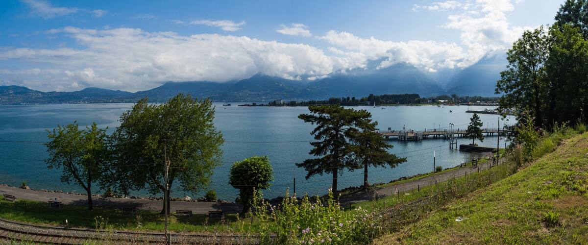 A lake with a dock, trees, and mountains in the background.