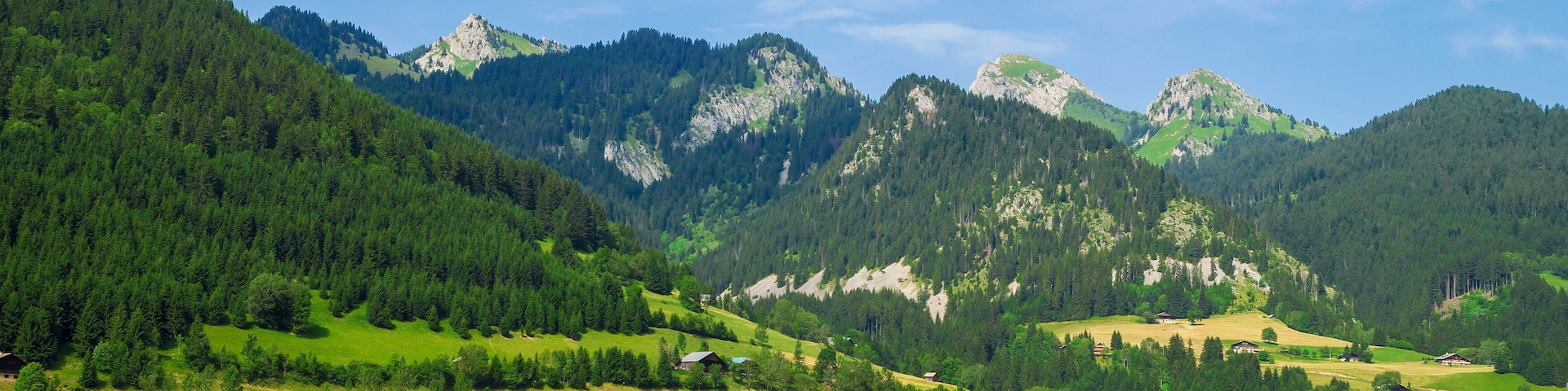 Uma aldeia montanhosa com casas de madeira, uma igreja e campos verdes.