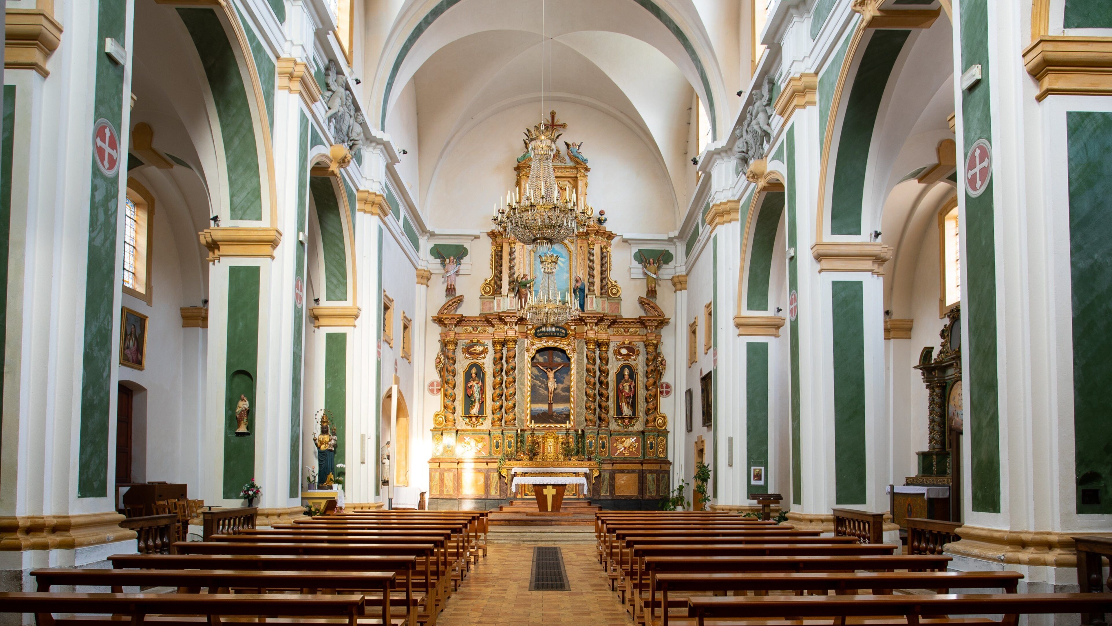 Interior ornamentado de una iglesia con un altar central, bancales y columnas verdes y blancas.