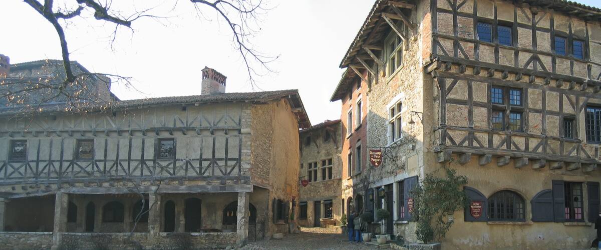 A narrow street with half-timbered buildings, cobblestone pavement, and a few pedestrians.