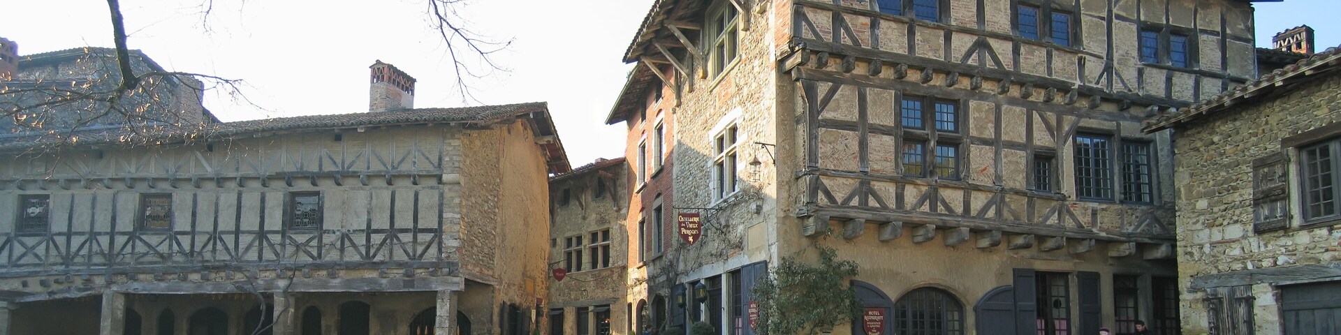 A narrow street with half-timbered buildings, cobblestone pavement, and a few pedestrians.