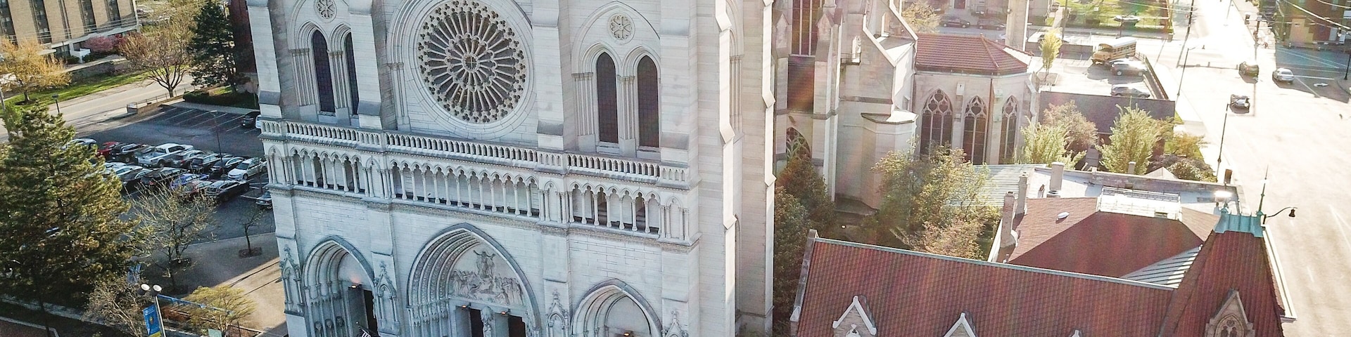 Uma grande catedral com uma rosácea destacada e um edifício menor adjacente com telhado vermelho.