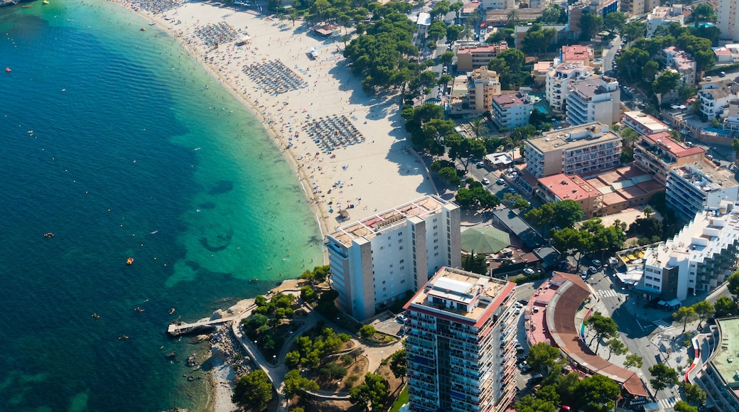 An aerial view of a coastal city with a beach, buildings, and a clear blue sea.