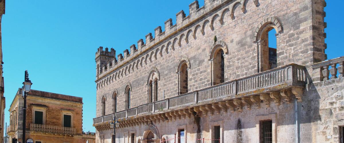 A historic stone building with arched windows and battlements.