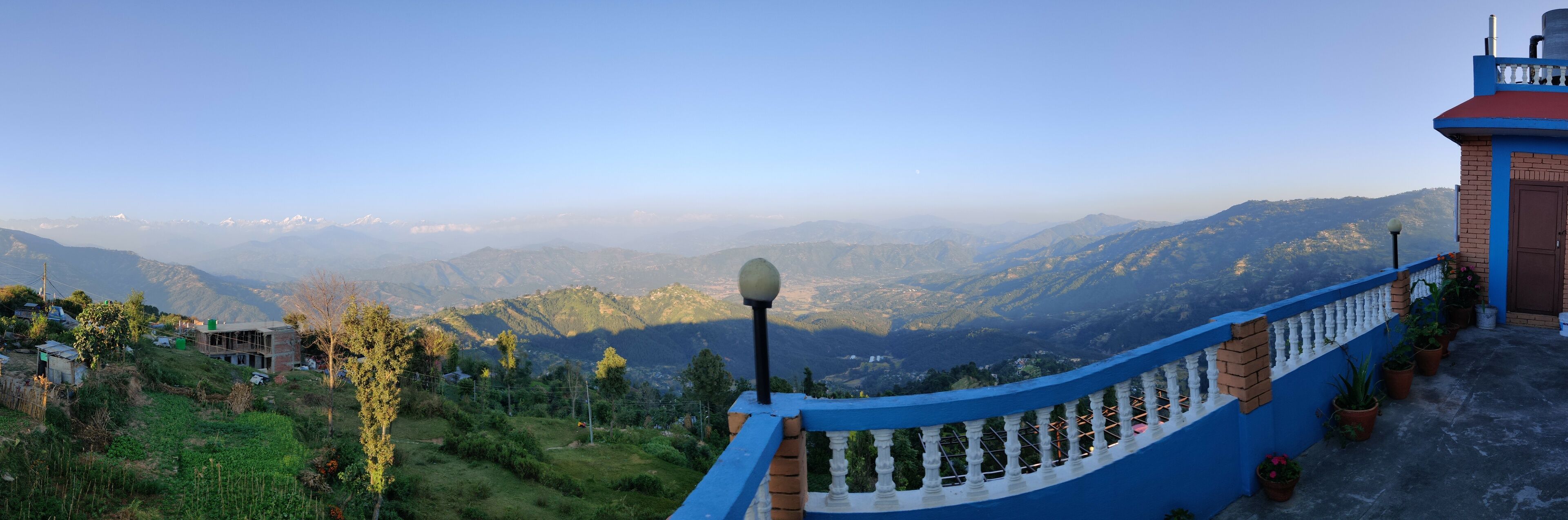 A mountainous landscape with a blue railing and a building with a red roof.
