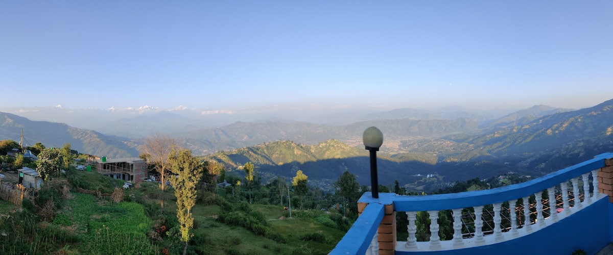 A mountainous landscape with a blue railing and a building with a red roof.
